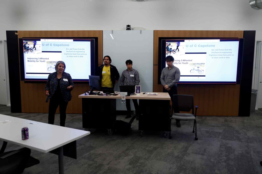 Four people stand in front of presentation screens