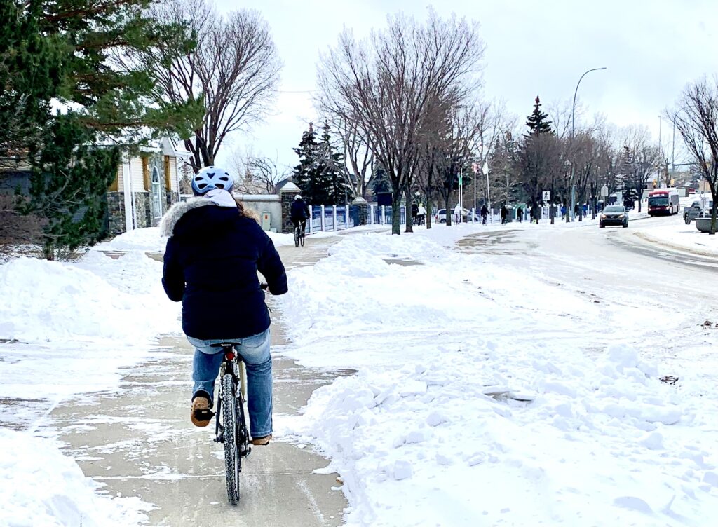students in parkas ride bikes along a snowy route